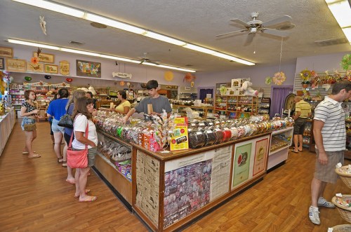 A busy candy store interior with customers browsing and a colorful display of sweets on the counter.