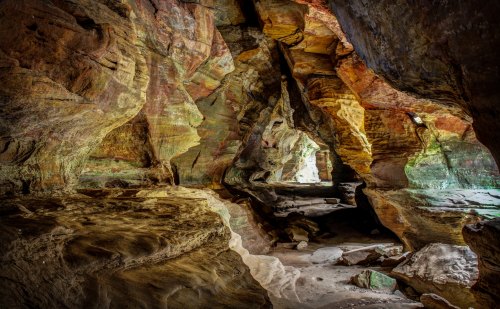 A colorful cave interior with textured rock formations and soft lighting illuminating the space.
