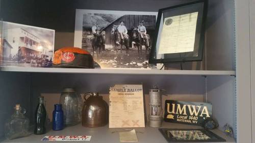 Display of historical mining artifacts, including photos, a ballot, and a miner's helmet, showcasing local heritage.