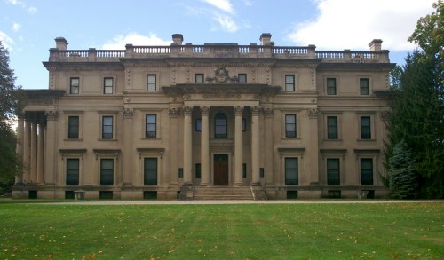 A grand, historic mansion with a symmetrical facade, large columns, and a well-manicured lawn in front.