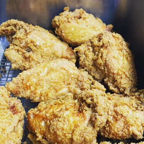 A close-up of crispy, golden-brown fried chicken pieces arranged in a tray.