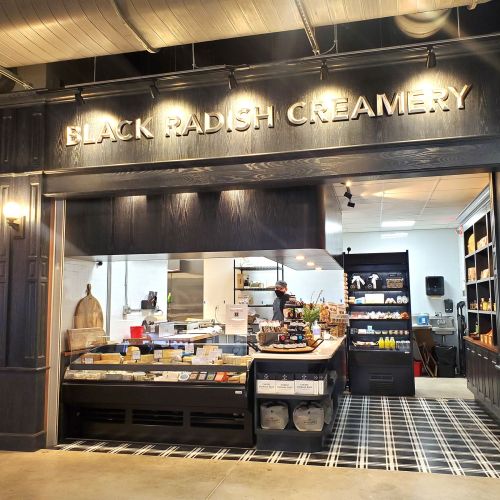 A storefront with the sign "Black Radish Creamery," featuring a display of products and a kitchen area visible inside.