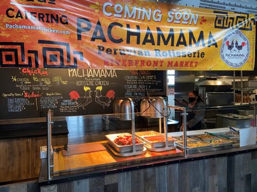 A colorful banner announces "Pachamama Peruvian Rotisserie" at a market, with a food display and menu in the background.