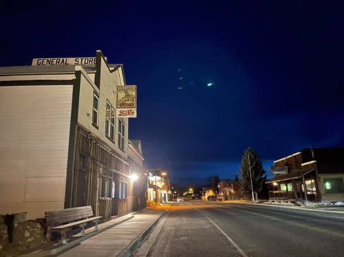 A quiet street at night featuring a general store and rustic buildings under a dark blue sky.