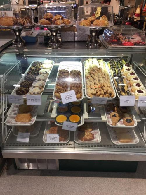 A display case filled with various pastries, cookies, and desserts, neatly arranged with labels.