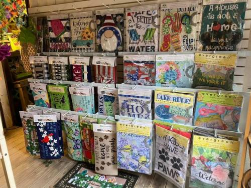 A display of colorful decorative signs and garden flags featuring various themes and sayings.