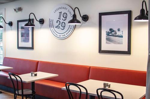 A cozy restaurant interior with orange seating, framed photos on the wall, and stylish black light fixtures.