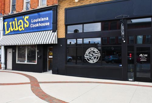Exterior view of Lula's Louisiana Cookhouse, featuring a striped awning and a modern black storefront.