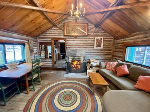 Cozy log cabin interior with a fireplace, wooden furniture, and a colorful circular rug. Warm and inviting atmosphere.
