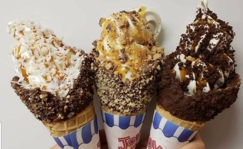 Three ice cream cones with various toppings: coconut, caramel, and chocolate, all in waffle cones.