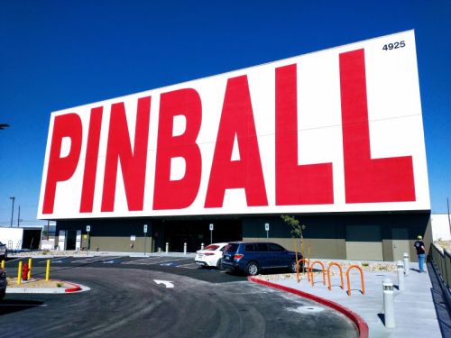 A large building with a bright red "PINBALL" sign on the front, set against a clear blue sky.