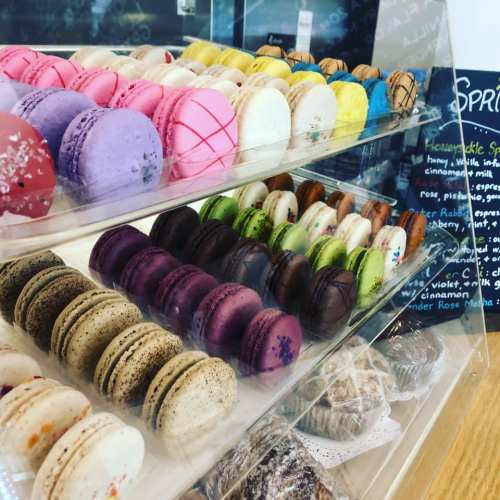A display case filled with colorful macarons in various flavors, arranged in neat rows.