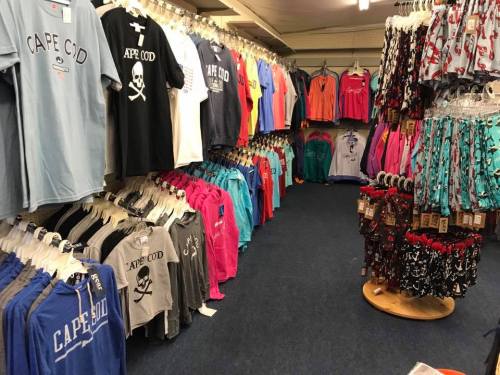 A clothing store aisle filled with colorful t-shirts and sweatshirts, featuring various designs and styles.