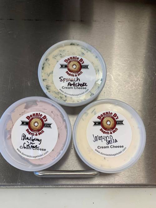 Three containers of cream cheese with labels: Spinach Artichoke, Blueberry, and Jalapeño.