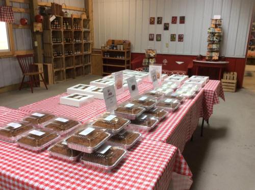 A rustic shop interior with a checkered tablecloth displaying various baked goods in clear containers.