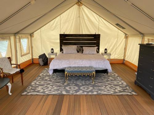 Cozy glamping tent interior featuring a bed, decorative rug, and stylish furniture. Warm, inviting atmosphere.