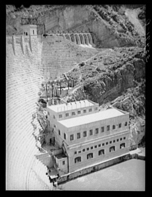 Historic black and white image of a hydroelectric power station set against a rocky landscape.