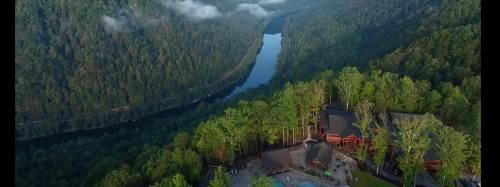 Aerial view of a lush green valley with a winding river and a resort nestled among trees.