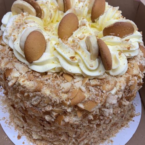 A round cake topped with whipped cream and cookies, surrounded by crushed cookies and decorated with vanilla wafers.