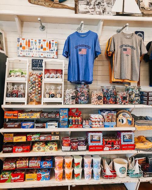 A colorful display of souvenirs, snacks, and apparel in a shop, featuring T-shirts and various candies.