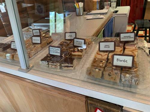 A display case filled with various types of fudge, labeled with names like "Blondie" and "Peanut Butter Swirl."