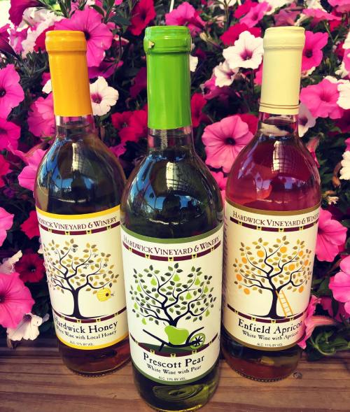 Three bottles of wine labeled Hardwick Vineyard & Winery, surrounded by vibrant pink flowers.
