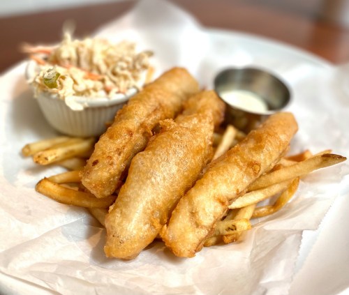 Three golden-brown fish fillets served with fries and a side of coleslaw in a white bowl.
