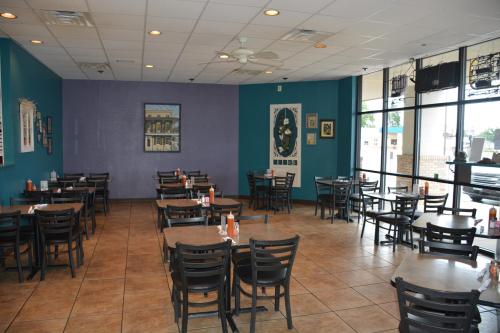 A spacious restaurant interior with blue walls, empty tables, and large windows letting in natural light.