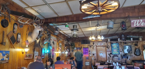 Cozy rustic restaurant interior with wooden walls, vintage decor, and diners enjoying their meals.
