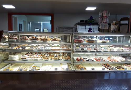 A display case filled with various desserts, including cakes, pastries, and sweets, in a bakery setting.