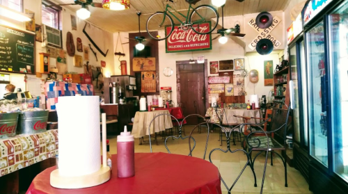 A cozy diner interior with vintage decor, including Coca-Cola signs, a bicycle, and tables set for dining.