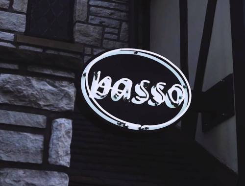 A circular sign with the word "passo" in a stylized font, mounted on a stone wall.