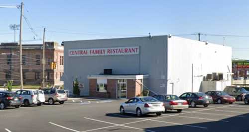 Exterior view of Central Family Restaurant, featuring a large building and a parking lot with several cars.