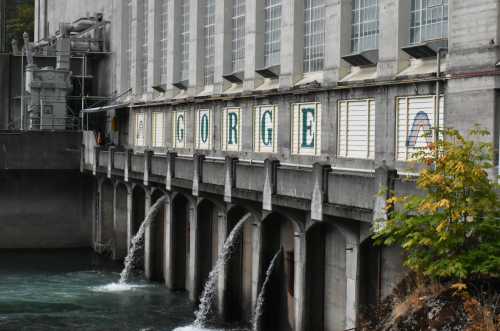 A concrete building with large windows and the word "GORGE" displayed on its side, with water flowing below.