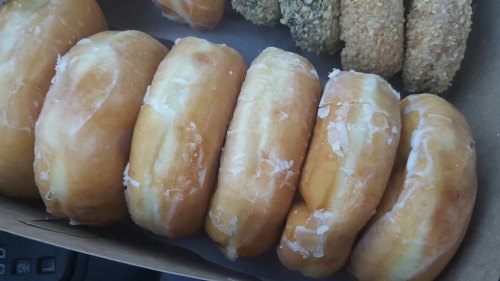 A close-up of glazed donuts arranged in a row, showcasing their shiny, sugary surface.