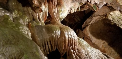 Stalactites and stalagmites in a dimly lit cave, showcasing unique rock formations and textures.