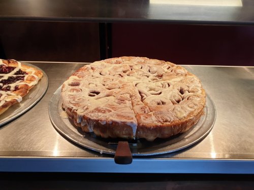 A freshly baked pie with a golden crust, sliced into pieces, displayed on a metal tray.