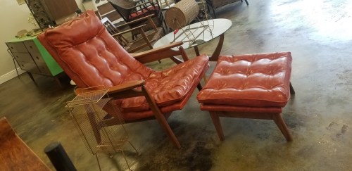 A vintage red leather lounge chair with an ottoman, set in a stylish, modern interior space.