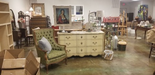 A vintage-style room filled with furniture, including a green chair, a dresser, and various decor items.
