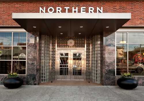 Entrance of a building with "NORTHERN" sign, featuring glass doors and modern architectural design.