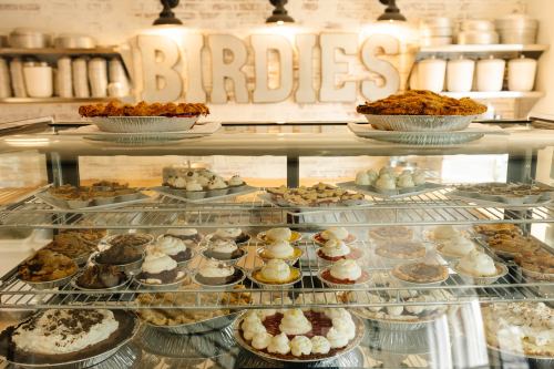 A display case filled with various pies and desserts, with the word "BIRDIES" in the background.
