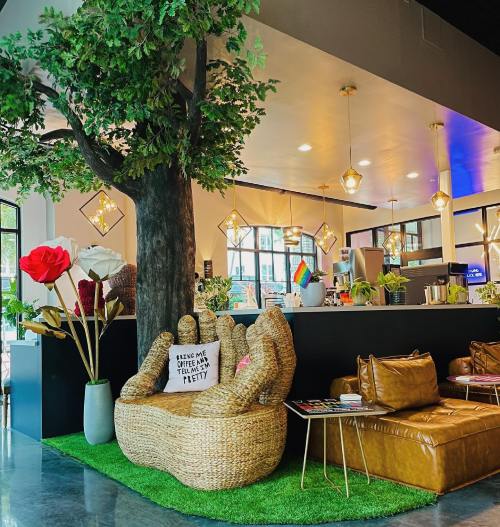 A cozy café interior featuring a large tree, unique seating, and colorful decor, creating a vibrant atmosphere.