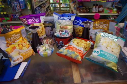 A colorful display of popcorn bags and snacks on a store counter, featuring various flavors and packaging.