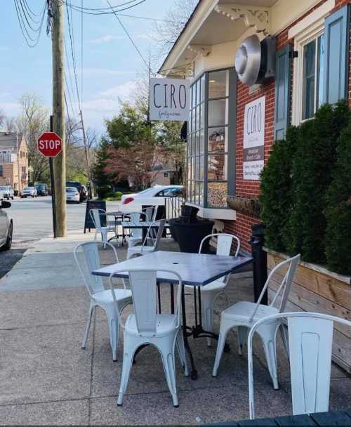 Outdoor seating area of a restaurant named "Ciro," with tables and chairs on a sidewalk near a stop sign.