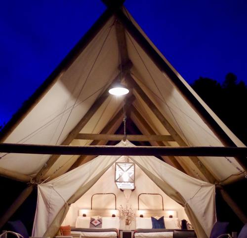 A cozy tent interior illuminated by soft light, set against a deep blue evening sky.