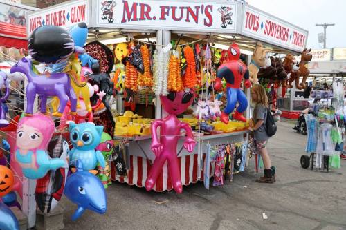 A colorful carnival stand filled with inflatable toys and souvenirs, with a person browsing nearby.