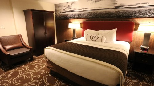 Cozy hotel room featuring a queen bed, armchair, and modern decor with a scenic wall mural.