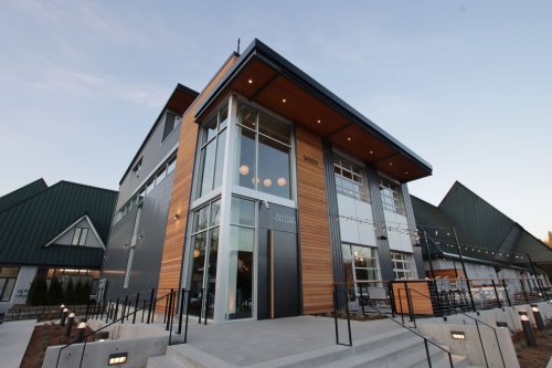 Modern building with large glass windows and wooden accents, featuring a welcoming entrance and outdoor steps.