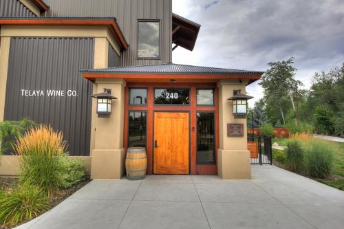 Entrance of Telaya Wine Co. featuring a wooden door, lanterns, and a barrel, set against a cloudy sky.