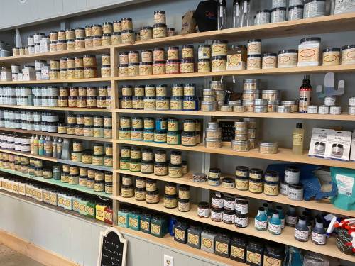 A neatly organized shelf displaying various jars and containers of products, labeled and arranged by size and type.
